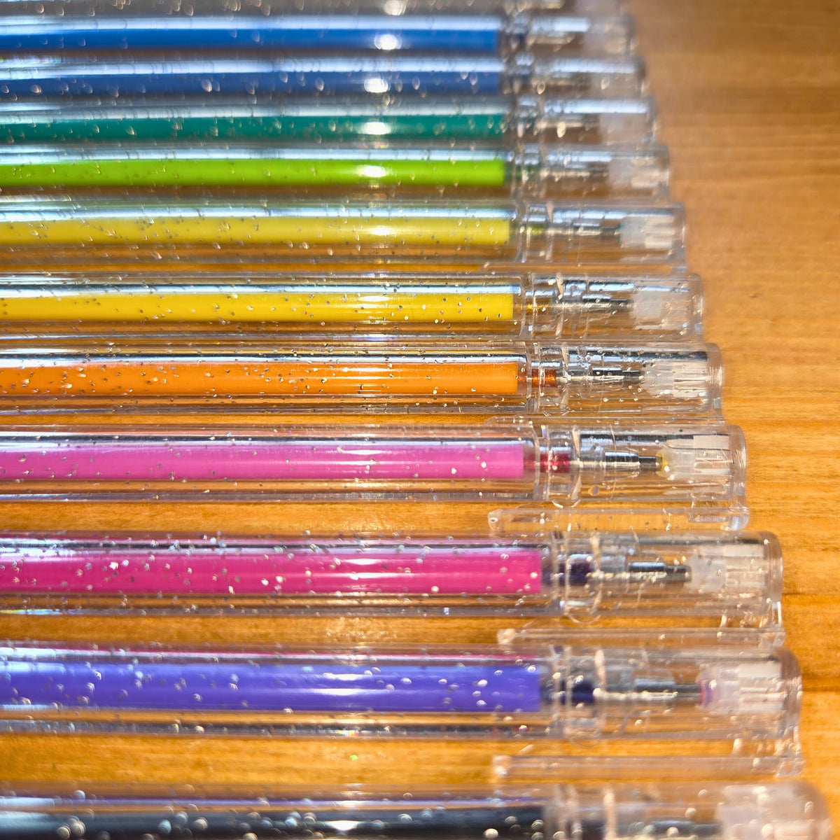 Set of colourful gel pens with clear accents on a wooden surface