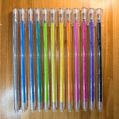 Row of colorful pens with glittery caps on a wooden surface
