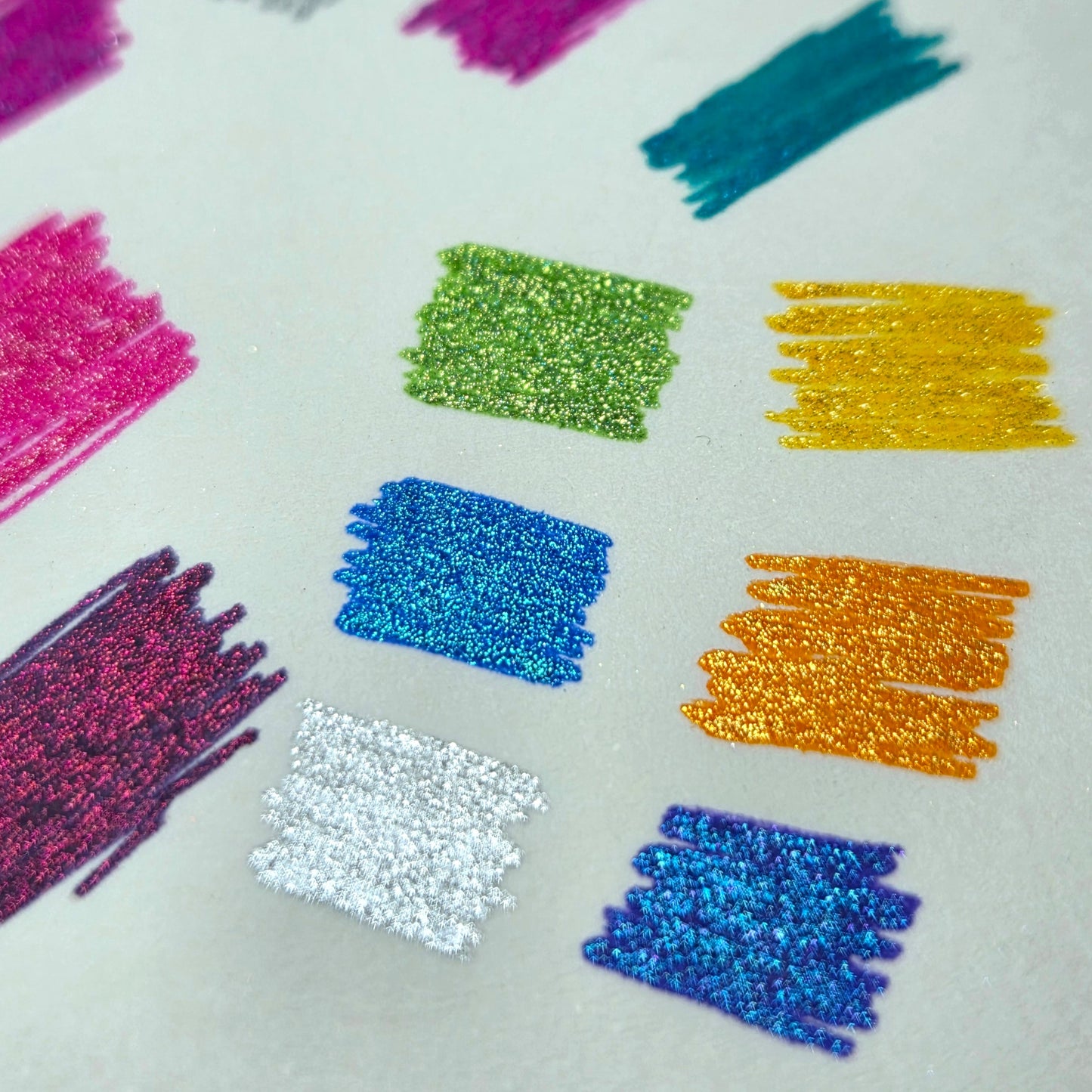 Colourful glittery pen strokes using The Artful Fox's Gemstone Gels on a white background